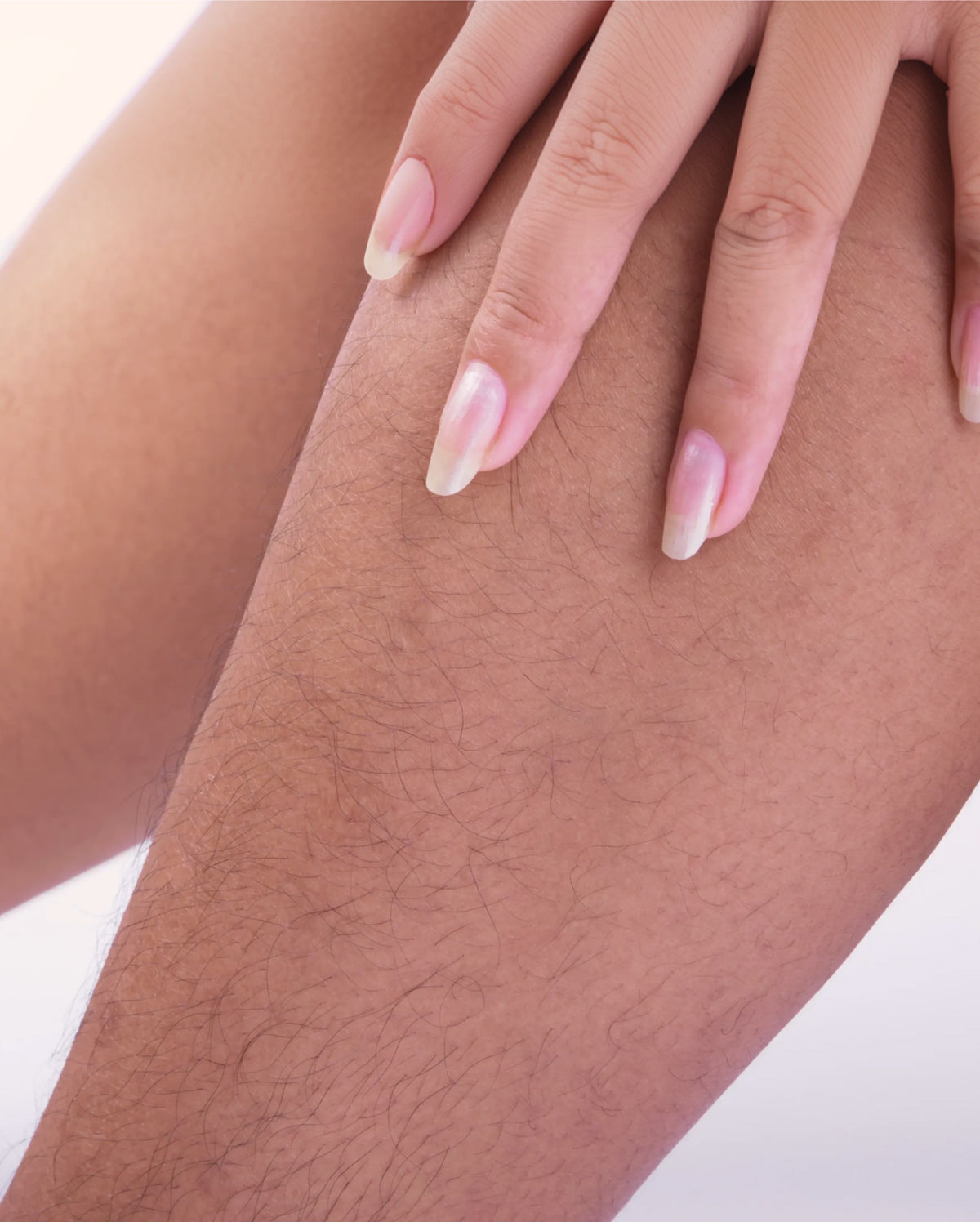 Main touchant une jambe avec des poils indésirables