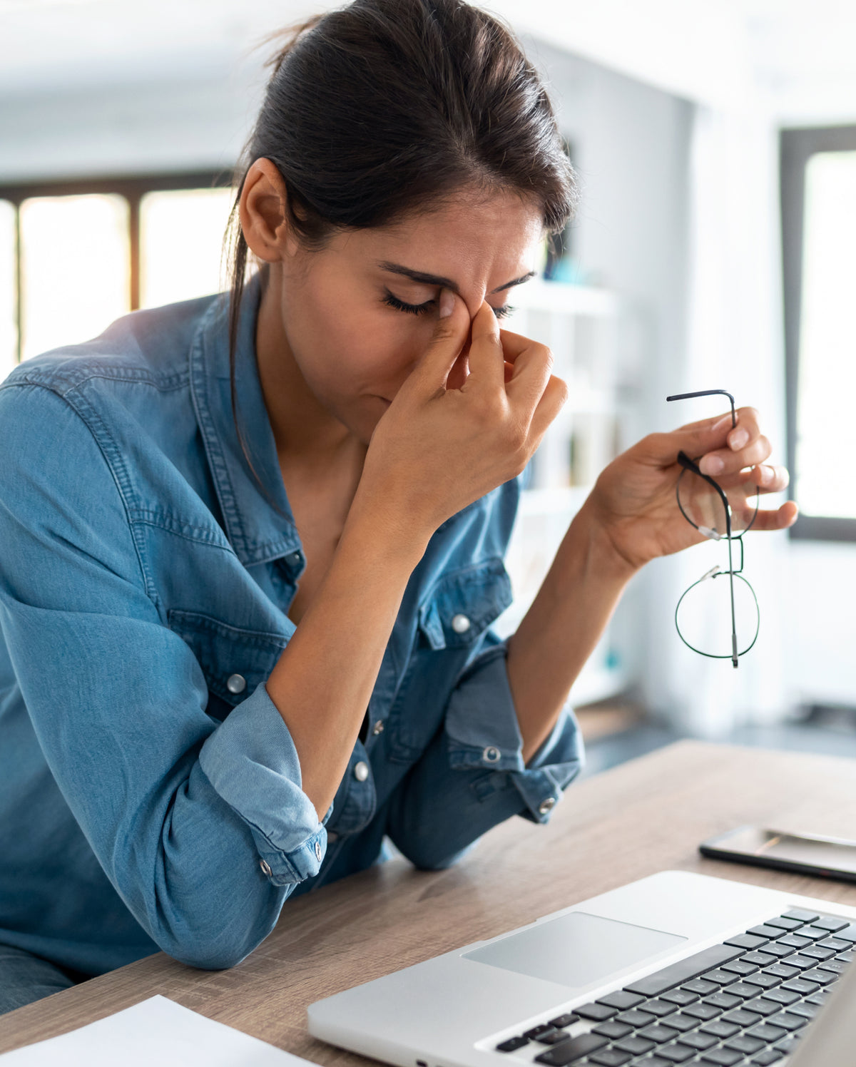 Femme stressée se massant le visage au bureau